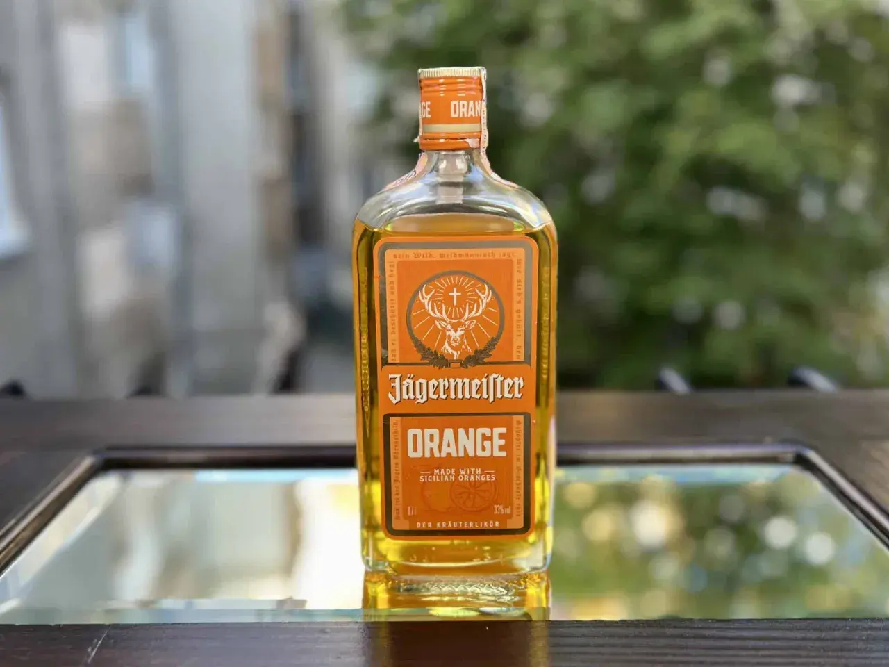 Butelka Jägermeister Orange na lustrzanym tle.