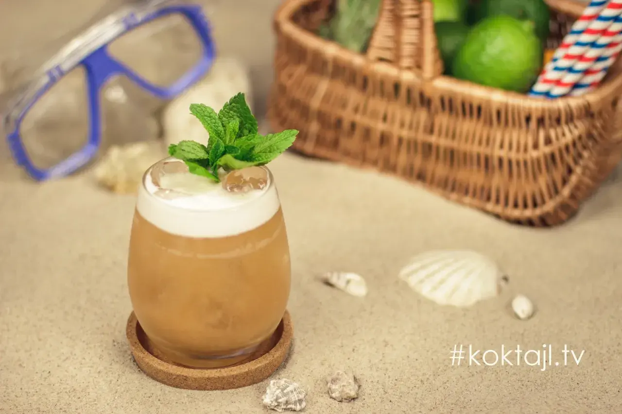 Orzeźwiający vodka sour z miętą na plaży, obok koszyka z limonkami i maski do nurkowania. Idealny na wakacje!
