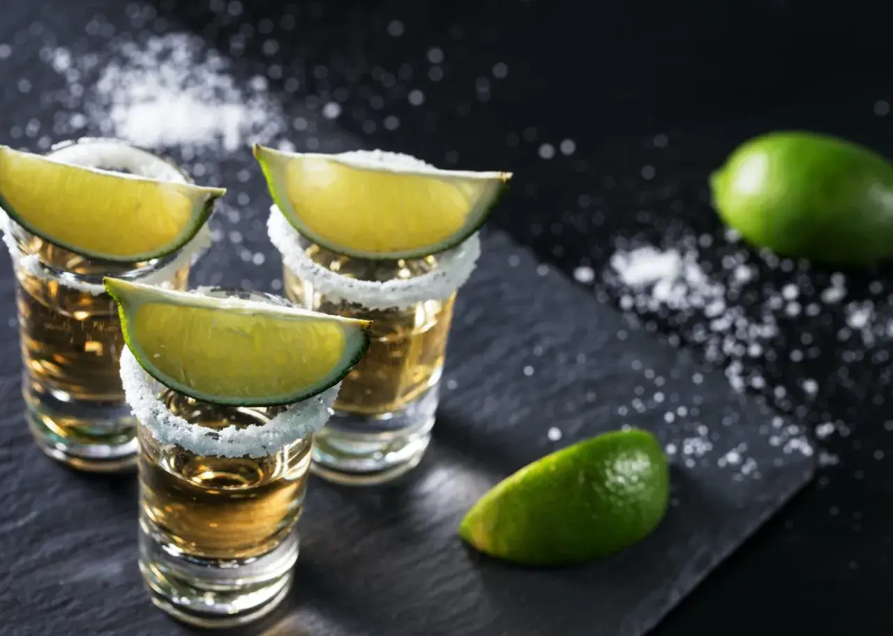 Trzy kieliszki tequili z solą i limonką, gotowe do degustacji. Oto jak pić tequilę, by poczuć jej smak.