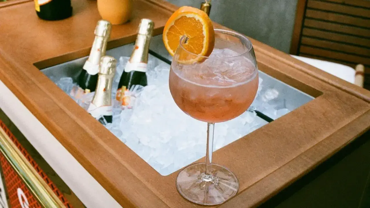 Orzeźwiający drink z pomarańczą i lodem, obok schłodzone butelki, idealne na aperitivo. Zastanawiasz się, jakie prosecco do Aperola?