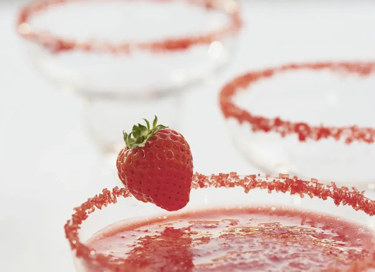 Truskawkowa margarita z ozdobnym brzegiem i świeżą truskawką.