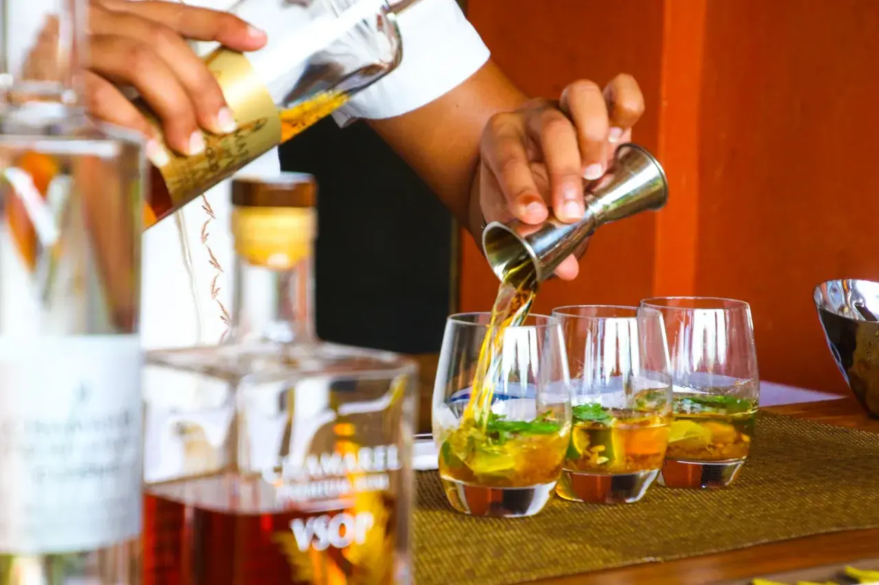Barman nalewa cachacę do szklanek z lodem i miętą.