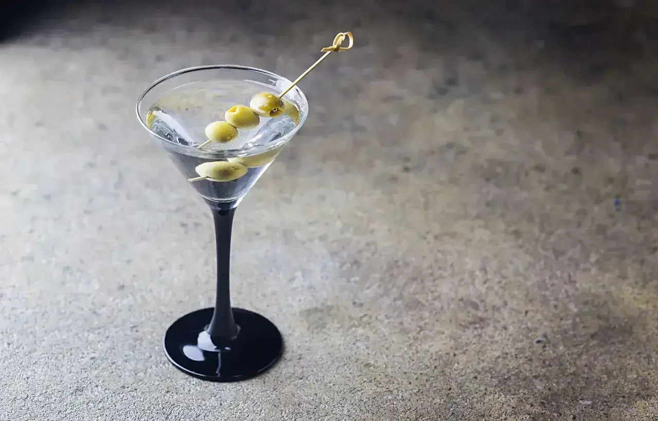 Elegancki dirty martini z trzema oliwkami na wykałaczce, gotowy do degustacji.