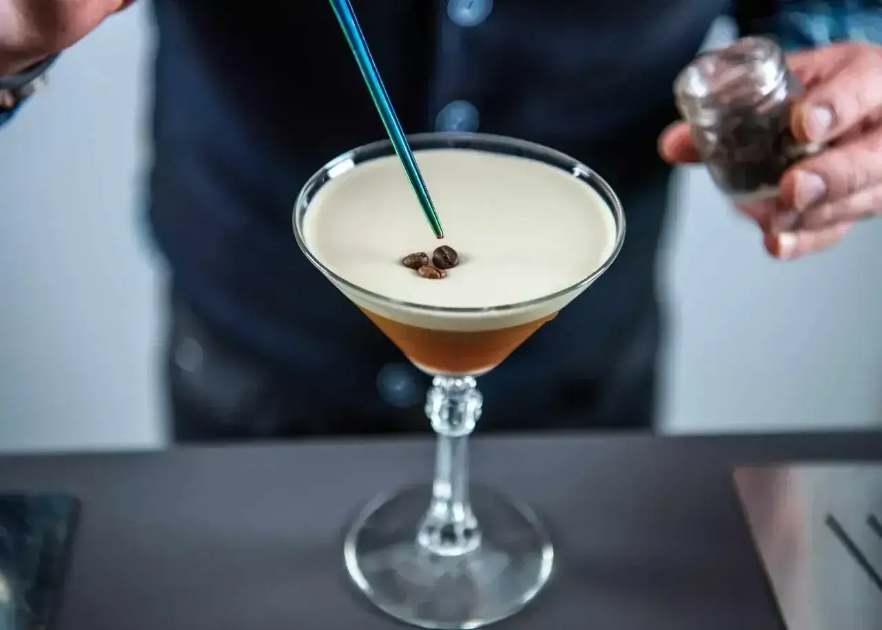 Barman dodaje ziarna kawy do drinka z pianką, przypominającego Espresso Martini. To właśnie kahlua co to za likier?