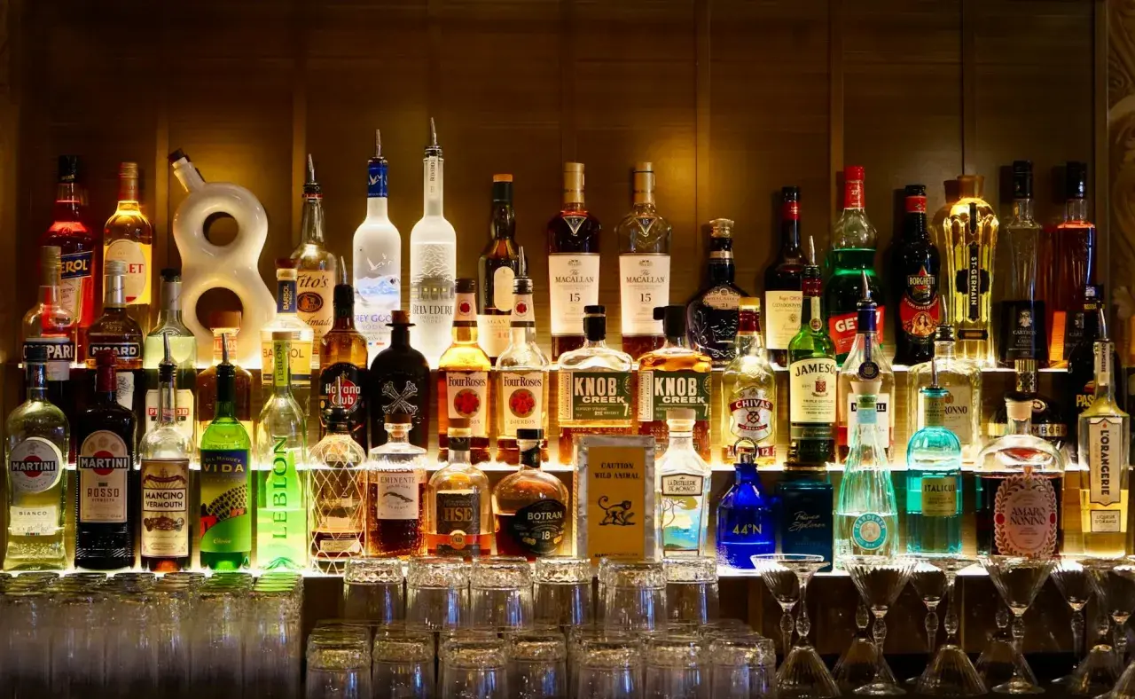 Rząd butelek alkoholi, w tym tequilla, na półce baru.