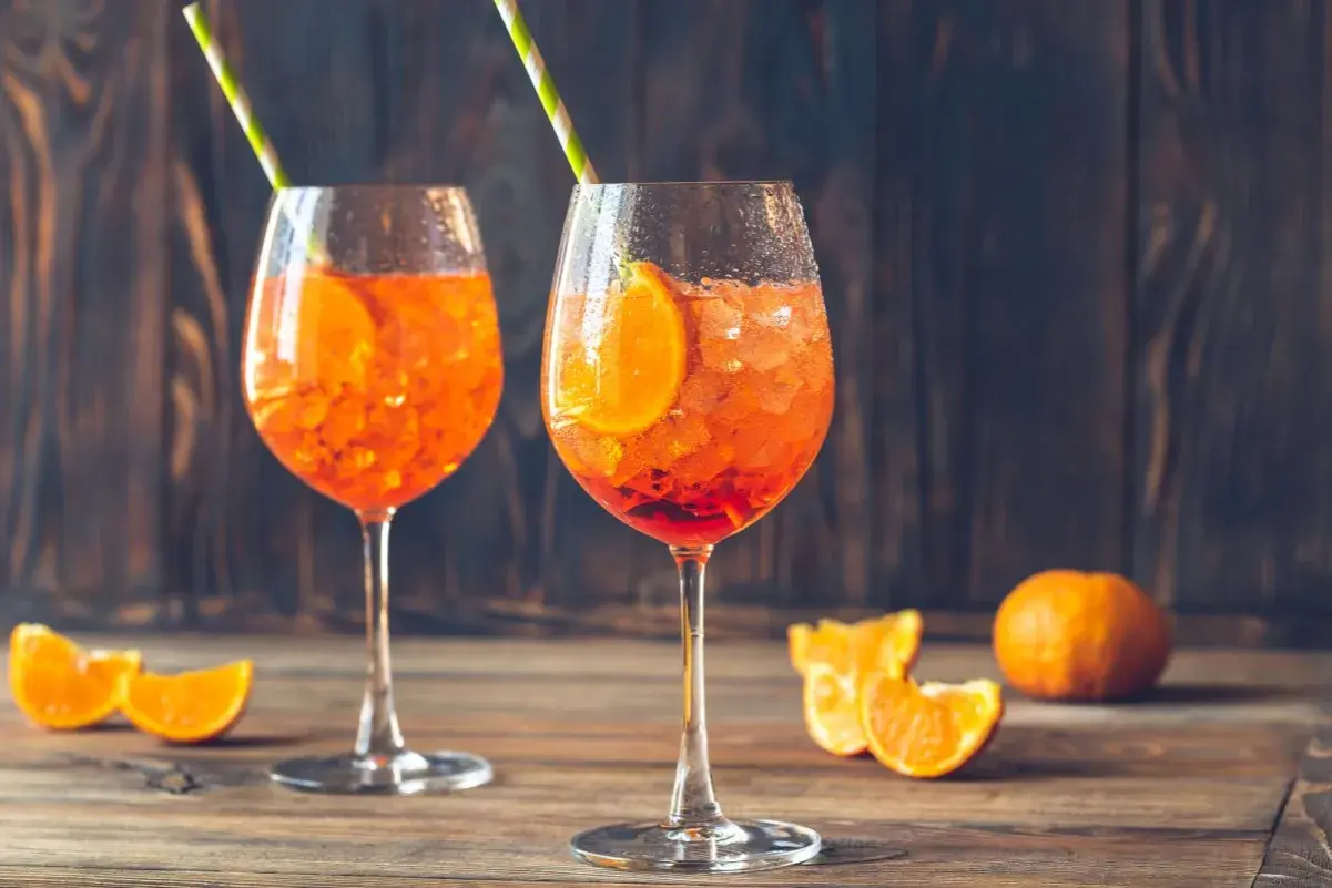 Dwa orzeźwiające drinki Aperol Spritz z plastrem pomarańczy i słomkami. Idealne na letnie popołudnie.
