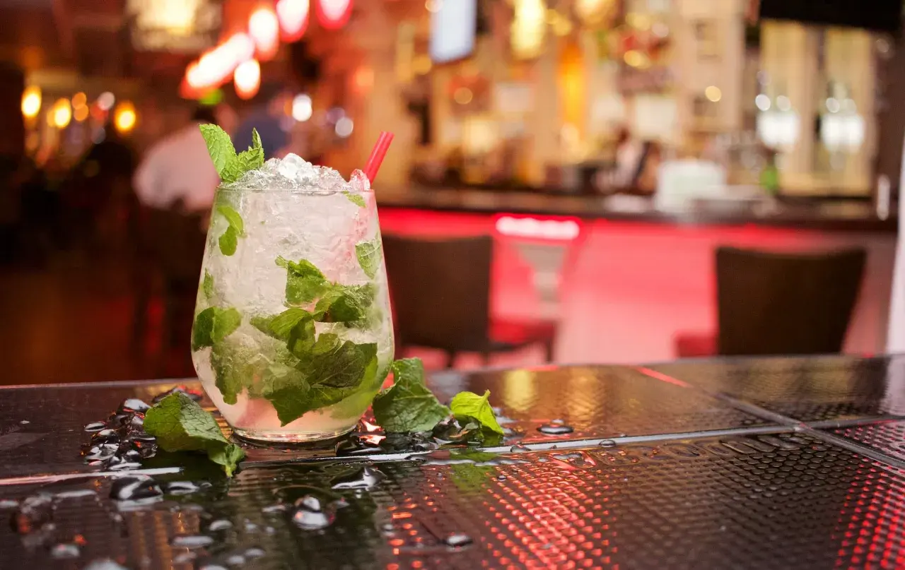 Szklanka orzeźwiającego mojito z miętą i lodem na barze.