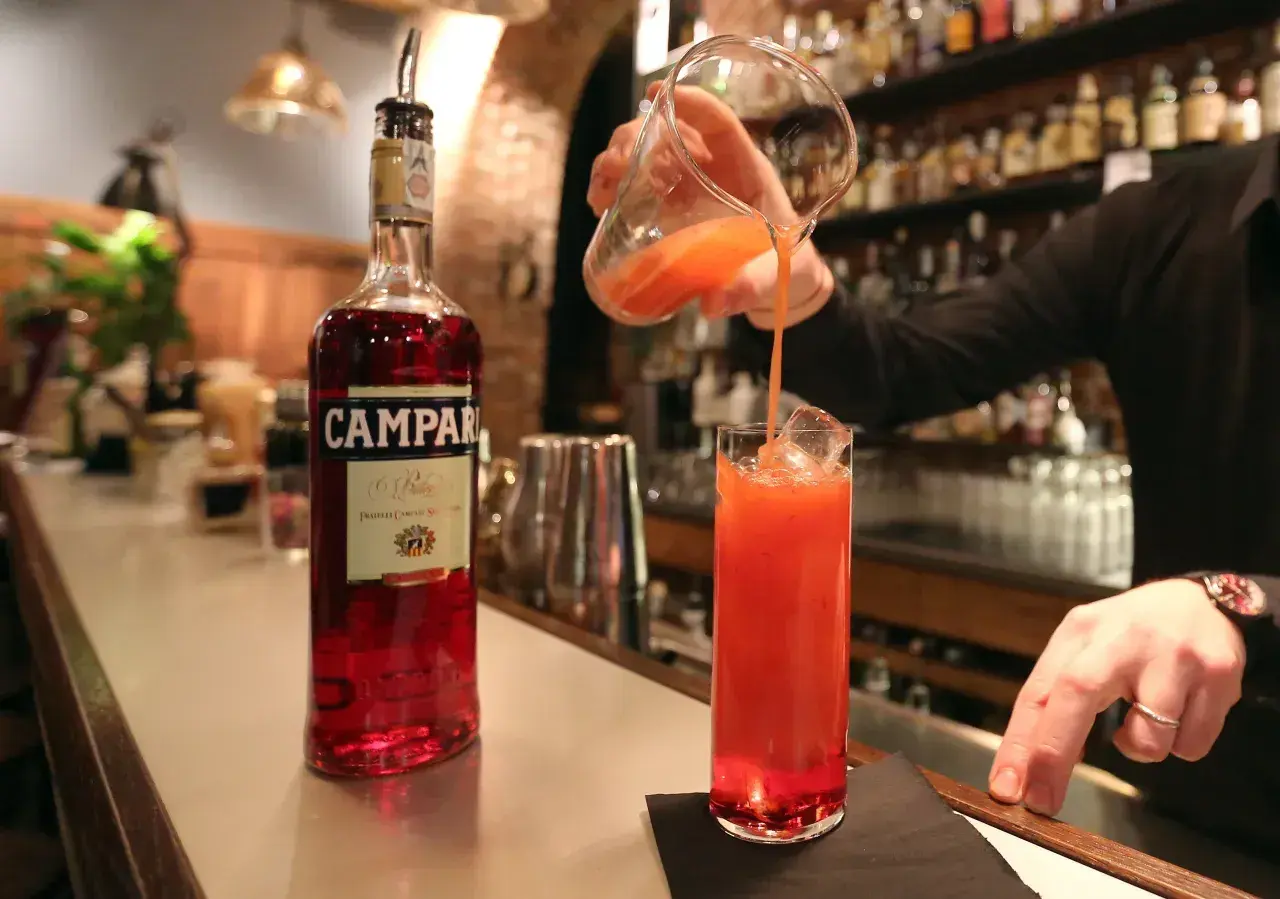 Barman nalewa czerwony koktajl z Campari do szklanki z lodem.