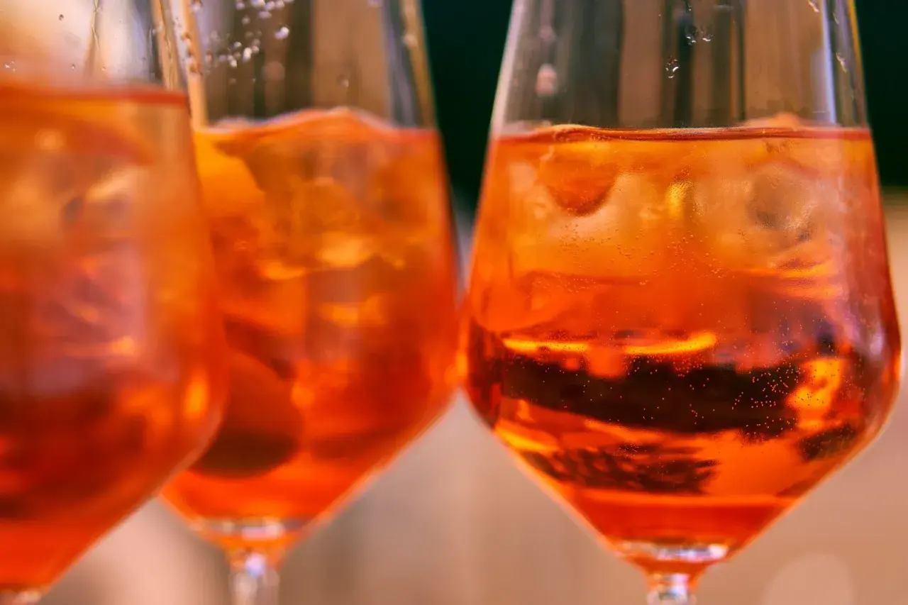 Orzeźwiający aperol bezalkoholowy z lodem w kieliszkach, idealny na letnie popołudnie.