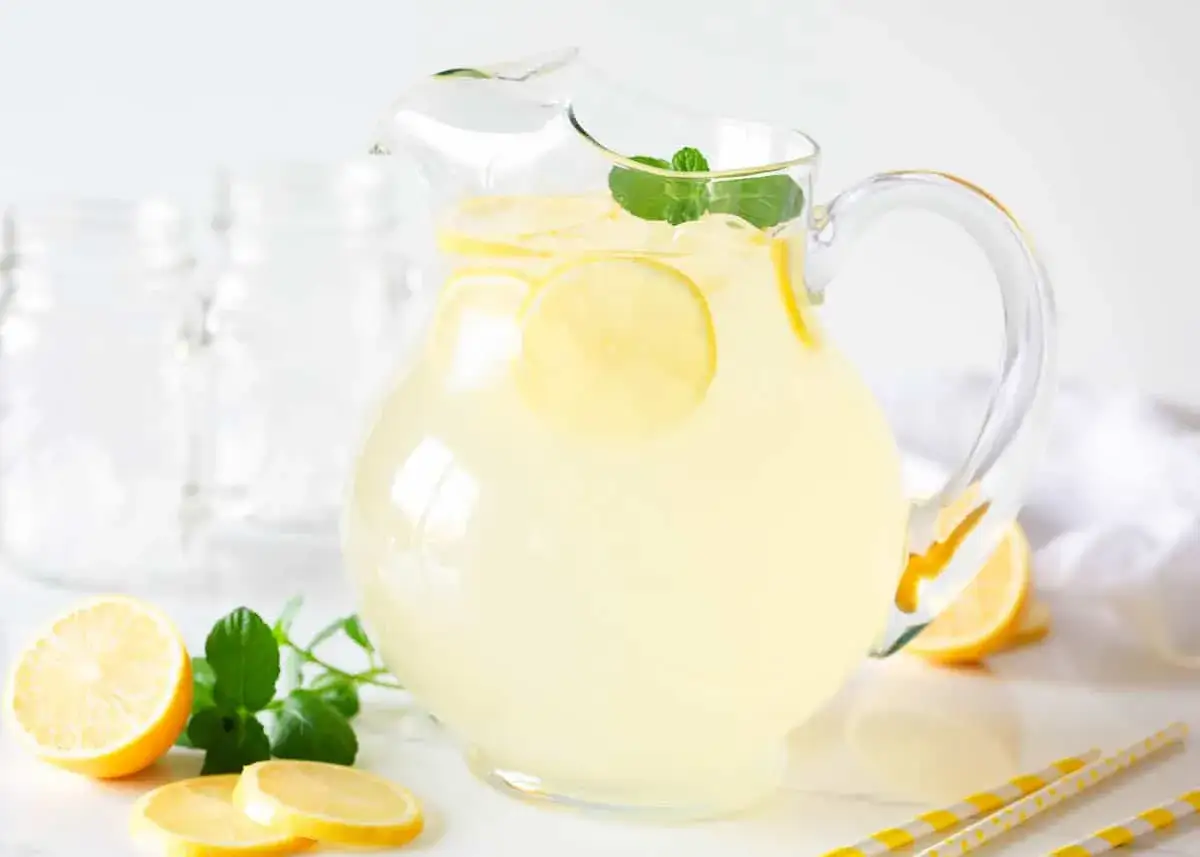 Jak zrobić lemoniadę? Orzeźwiająca, domowa lemoniada w dzbanku, ozdobiona plasterkami cytryny i miętą. Idealna na upalne dni.
