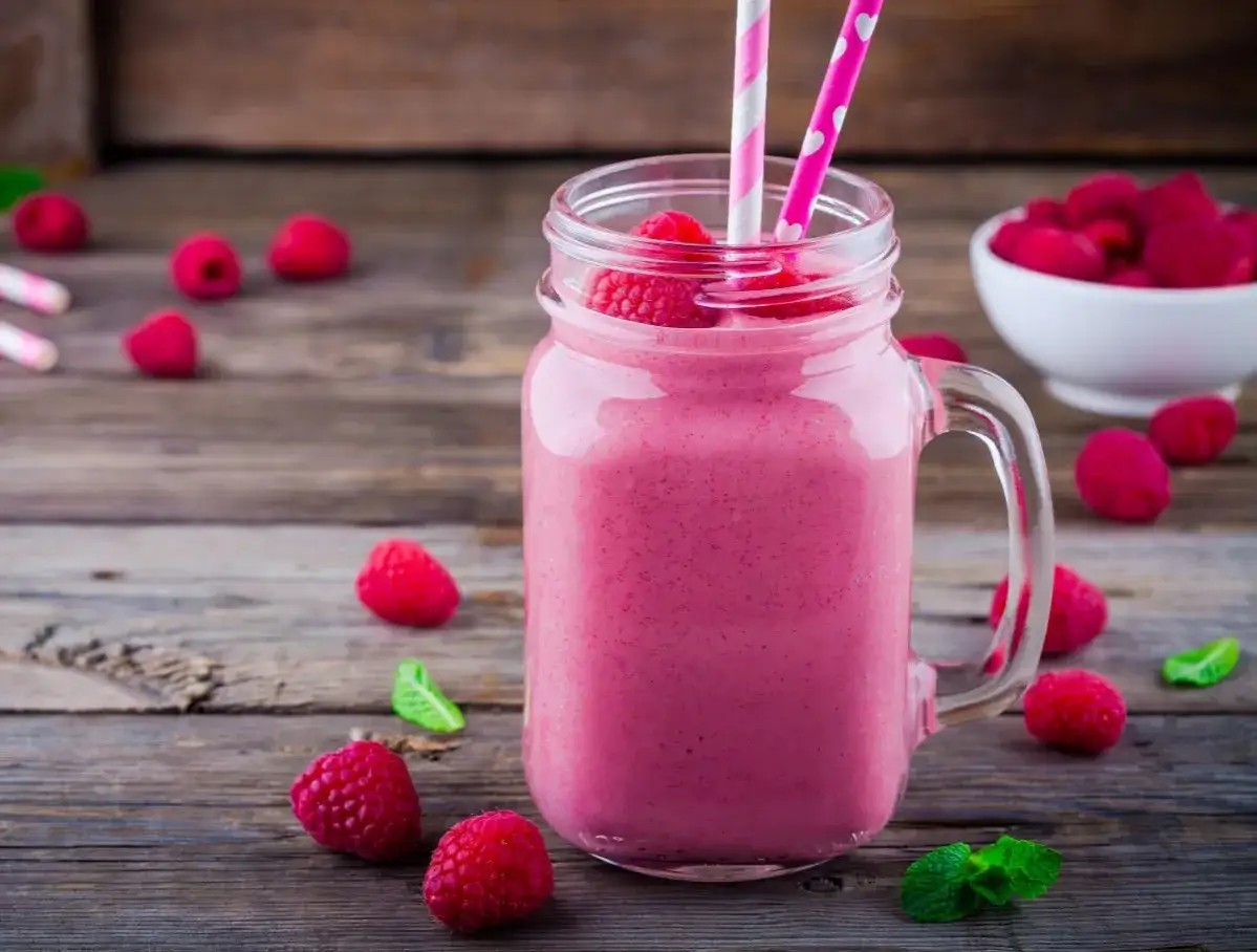 Różowy koktajl malinowy w słoiku, ozdobiony świeżymi malinami i miętą. Idealny na letnie orzeźwienie, smakuje jak Chambord.