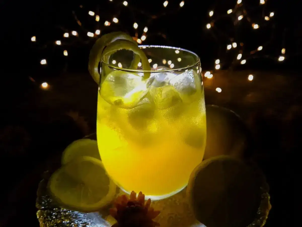 Orzeźwiający drink z limoncello, lodem i cytrynową skórką, otoczony migoczącymi światełkami.