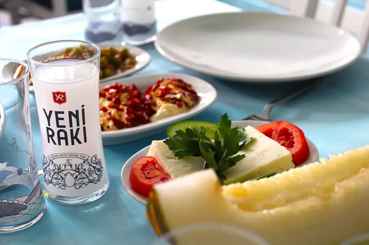 Szklanka Yeni Raki, ser, pomidor, ogórek i melon na stole.