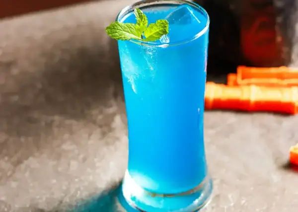 Błękitny drink z Blue Curaçao, lodem i miętą w szklance.